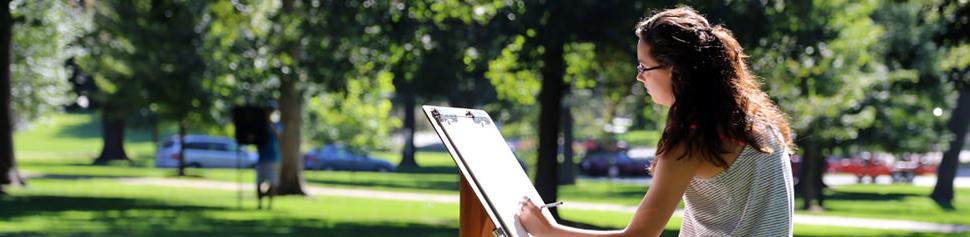 女学生在校园前草坪的画架上画画